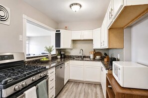 A compact kitchen with white cabinets, a black stove, and a microwave.