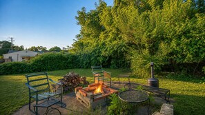 An outdoor seating area with a fire pit, chairs, and a table.