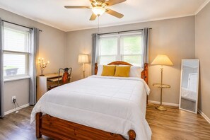 A bedroom with a bed, bedside lamps, a ceiling fan, and a mirror.