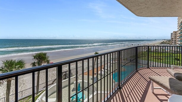 Een balkon met uitzicht op strand en zee.