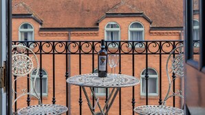 A balcony with wrought iron railings, a round table with a bottle and glass, and a brick building in the background. - Clifford St - Apartment 8 - sleeps 4 guests  in 2 bedrooms (York)