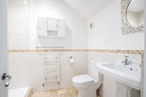 Un baño con inodoro, lavamanos y espejo.