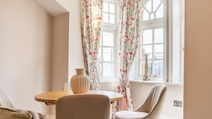 A dining area with a round wooden table, two chairs, and a vase on the windowsill. - Clifford St - Apartment 8 - sleeps 4 guests  in 2 bedrooms (York)