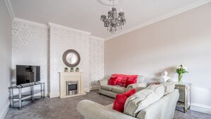 A living room with a fireplace, a sofa, a TV, and a chandelier. - Clifford St - Apartment 8 - sleeps 4 guests  in 2 bedrooms (York)