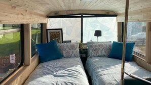 A cabin with two beds, a window, and a view of the outside. - Ballinadee Bus - Boutique Bus Accommodation (Ballinadee)