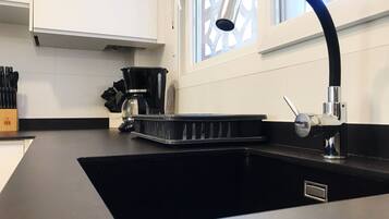 Een moderne keuken met een zwart spoelbak, een koffiezetapparaat en een raam met decoratief spijlenwerk.