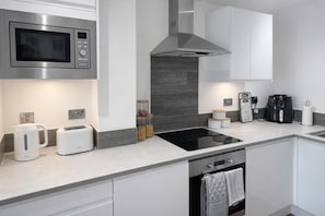 A modern kitchen with a built-in microwave, toaster, kettle, and coffee maker.