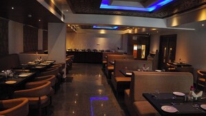 Un restaurant avec des banquettes et des tables, un bar et un comptoir d’accueil.