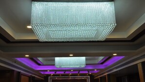 Un plafond orné d’un grand luminaire aux motifs géométriques en forme de losanges, qui diffuse une lumière vive.