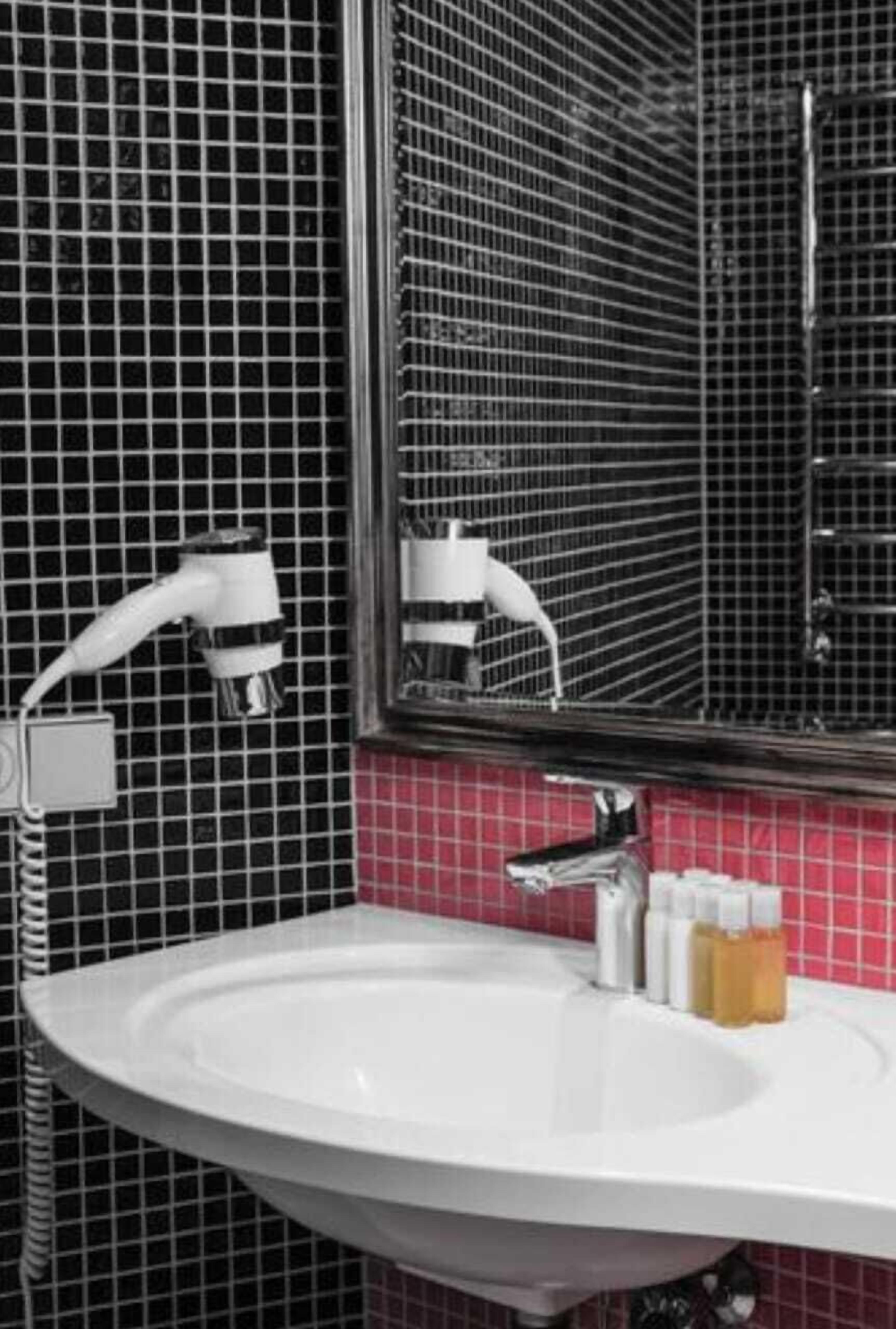Un baño con lavamanos blanco, un espejo y una ducha.
