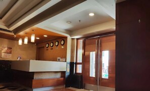 A reception area with a counter, clocks, and a patterned floor. - Hotel Thanmayi Inter National (Vijayawada)