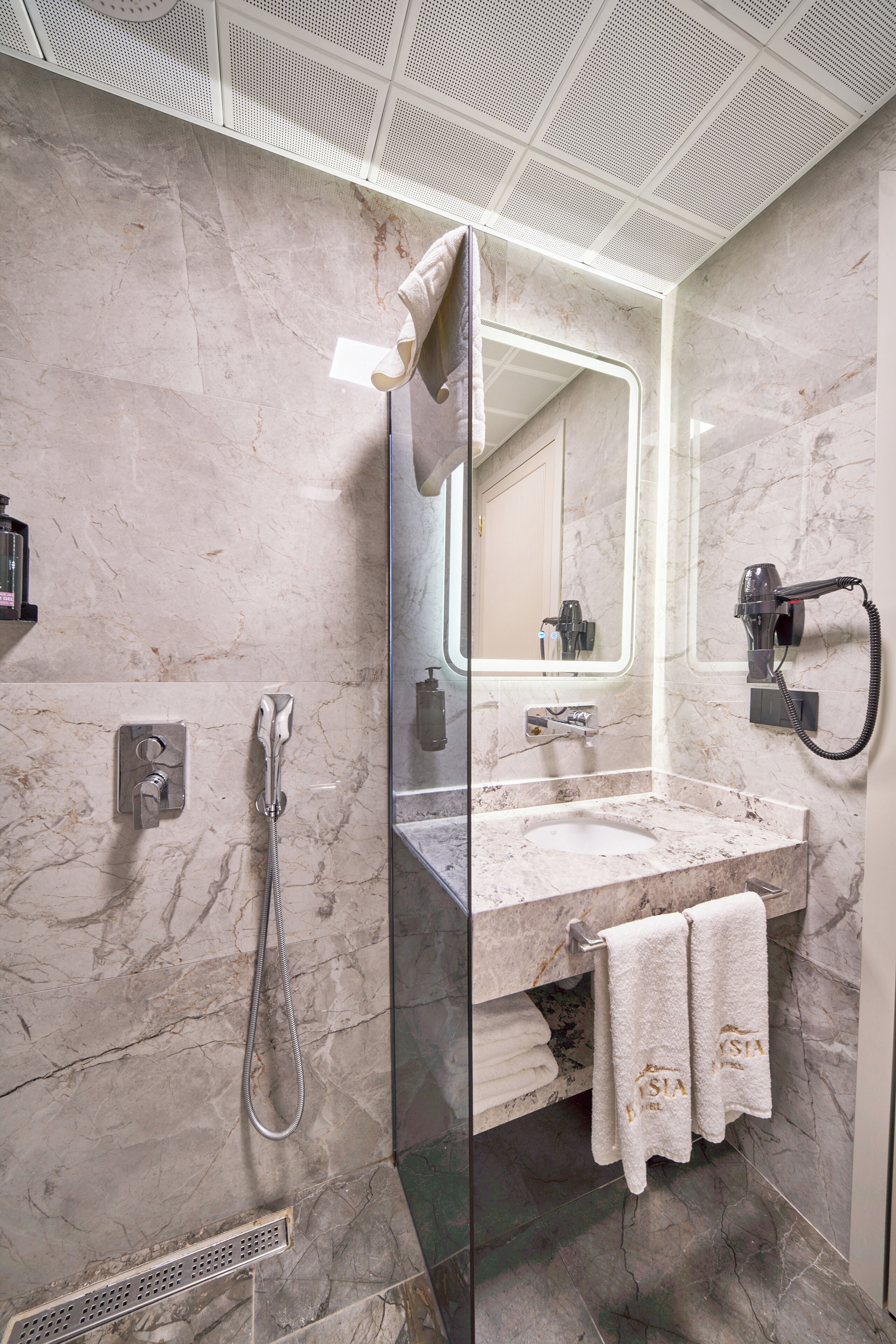 A modern bathroom with a glass-enclosed shower, a vanity with a sink, and a large mirror.