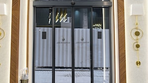 A hotel entrance with a glass door, a black doormat, and a hanging light fixture. - Elysia Hotel (Istanbul)