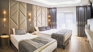 A hotel room with two beds, a round side table, a flat-screen TV, and a large window with curtains. - Elysia Hotel (Istanbul)