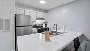 A modern kitchen with white cabinetry, stainless steel appliances, and a wooden knife block on the countertop.
