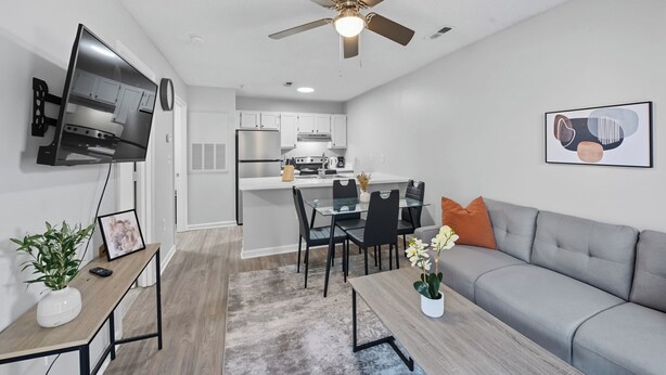 A modern living room with a grey sofa, a coffee table, and a TV mounted on the wall.