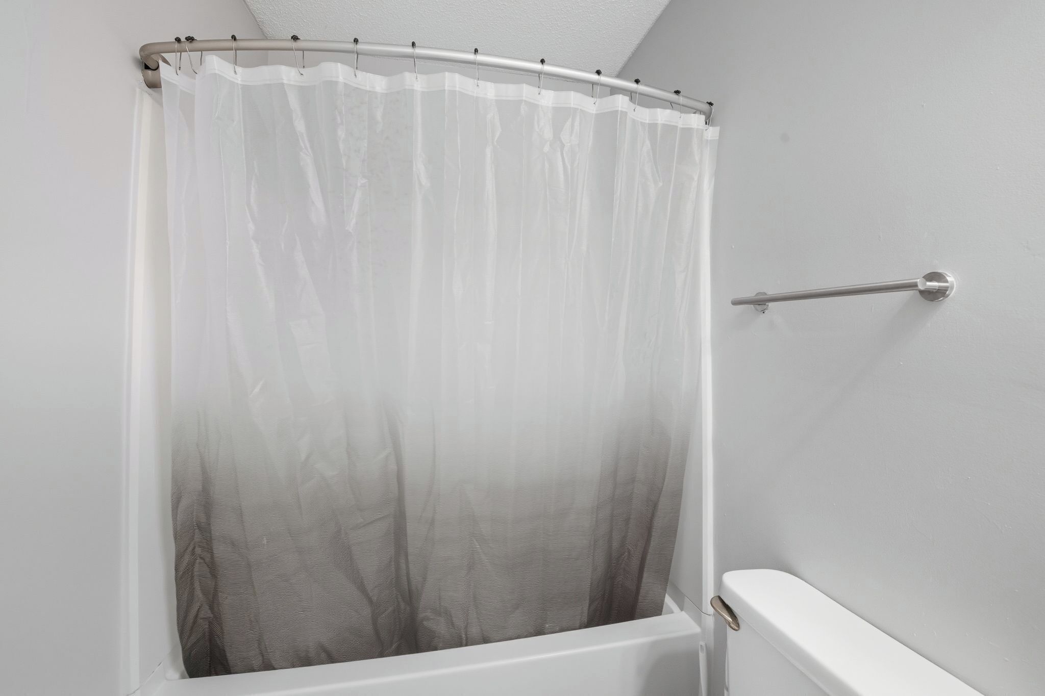 A bathroom with a shower curtain, a towel rack, and a white bathtub.