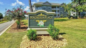 Letrero de Magnolia Place, con un edificio de piedra al fondo.