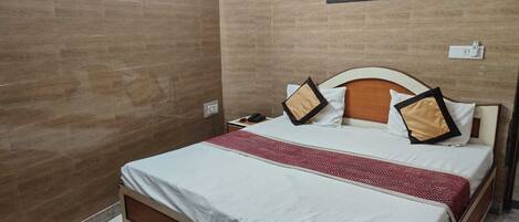 A hotel room with a bed, a nightstand, a wall-mounted phone, and a decorative wall panel.