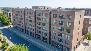 A multi-story building with a brick facade, large windows, and a flat roof.