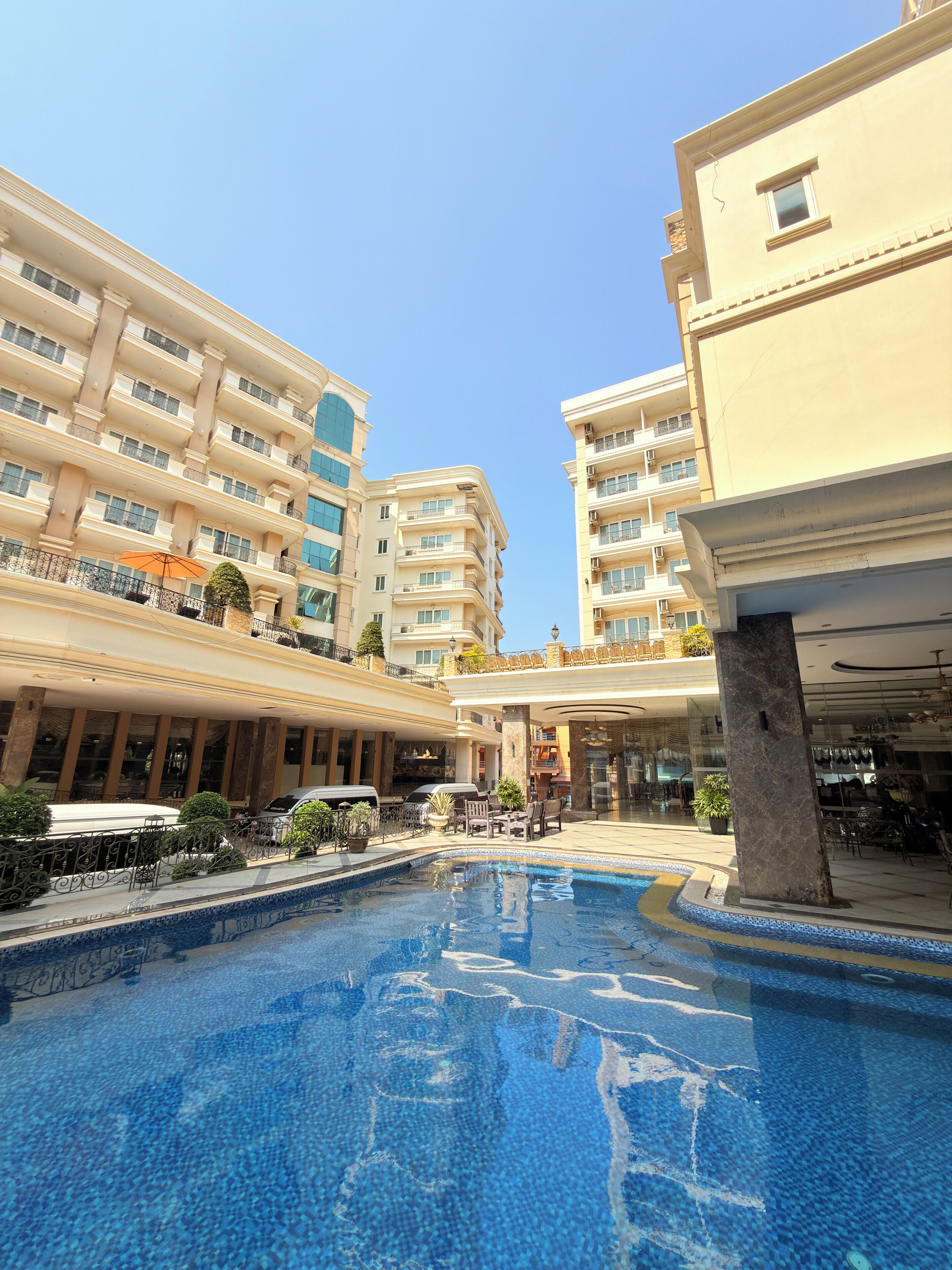 A hotel with a swimming pool, multiple balconies, and outdoor seating areas.