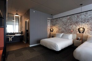 Une chambre d’hôtel moderne avec un grand lit, une salle de bain séparée dotée d’un lavabo et d’un mur orné d’un motif décoratif.