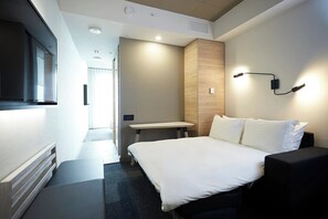 A modern hotel room with a large bed, a desk, and a TV.