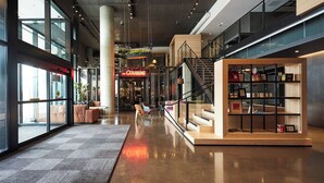 A modern interior with a central staircase, a seating area with sofas, and a display of items on shelves. - Modern Room Perfect for Business Stays w/ Workspace + Dining Table Included (Brossard)