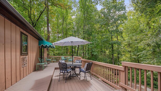 A wooden deck with a table and chairs, surrounded by a wooden railing and trees. - Nature Lovers Serene Get-A-Way RANCH in North Raleigh (Raleigh)