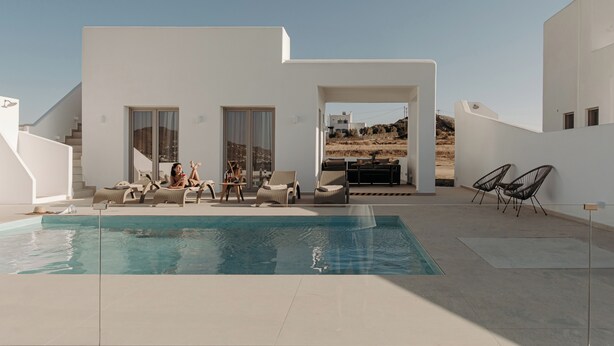Un espace piscine extérieur moderne, doté d’une piscine à l’eau d’un bleu limpide, de chaises longues et d’un coin salon avec une table et des chaises.