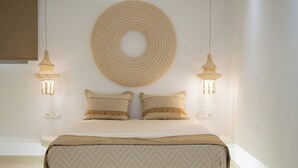 Un lit bien fait, recouvert d’une couvre-lit à motifs, avec deux oreillers et une grande tapisserie tissée accrochée au mur au-dessus.