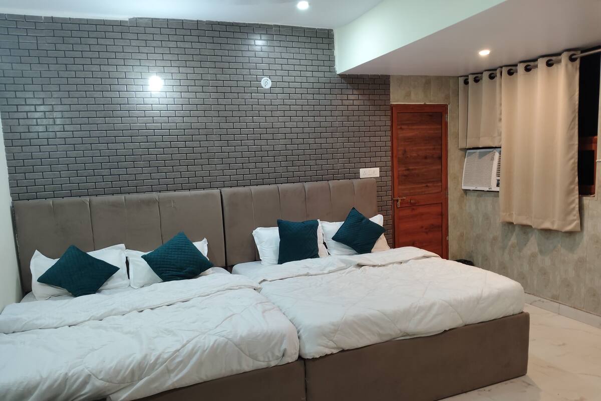 Ein modernes Schlafzimmer mit einem Ziegelmuster-Kopfstück, einem großen Bett mit weißer Bettwäsche und Türkis-Kissen sowie einer Holztür.
