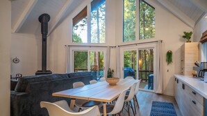 A modern kitchen with a large window, a dining area with a wooden table and white chairs, and a built-in stove.