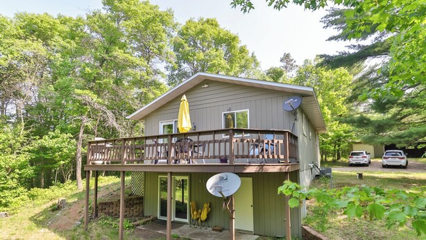 Una piccola casa a un piano con una veranda, un'antenna parabolica e un garage.