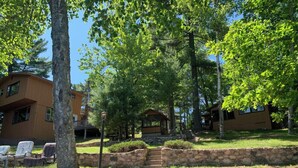 A lodge with stone steps leading to a covered area, surrounded by lush greenery and trees.