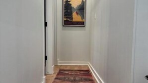 A hallway with a patterned carpet and a framed picture on the wall.