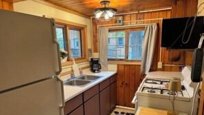 Una cocina compacta con armarios de madera, un lavamanos, una estufa y una pequeña encimera.
