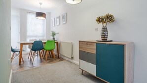 Eine moderne Küche mit Essbereich, ausgestattet mit einem Holztisch, zwei Stühlen, einem Schrank und einer Vase mit getrockneten Blumen.