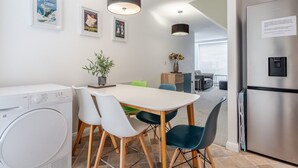 Eine moderne Küche mit Waschmaschine, Esstisch und Stühlen sowie einem Kühlschrank.