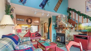 Un salon chaleureux avec une cheminée, des meubles à motifs écossais et un téléviseur.