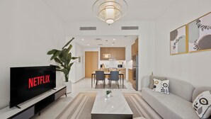A modern living room with a flat-screen TV, a coffee table, and a sofa. - WYZ RENT|Earthy Elegant 1BR Surf 2 Creek Beach (Dubai)