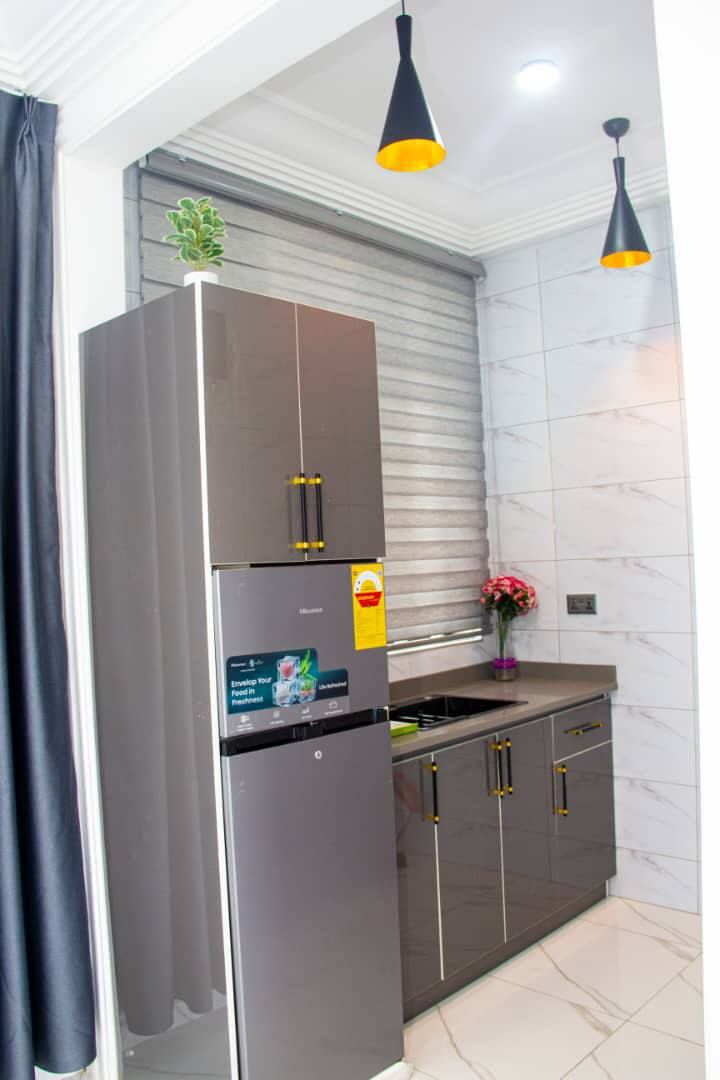 A modern kitchen with a stainless steel refrigerator, dark cabinets, and two pendant lights.