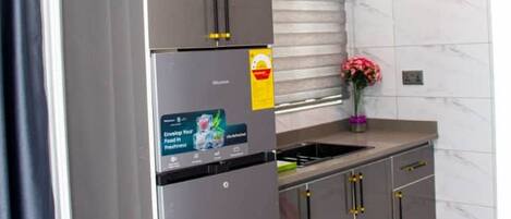 A modern kitchen with a stainless steel refrigerator, dark cabinets, and two pendant lights.