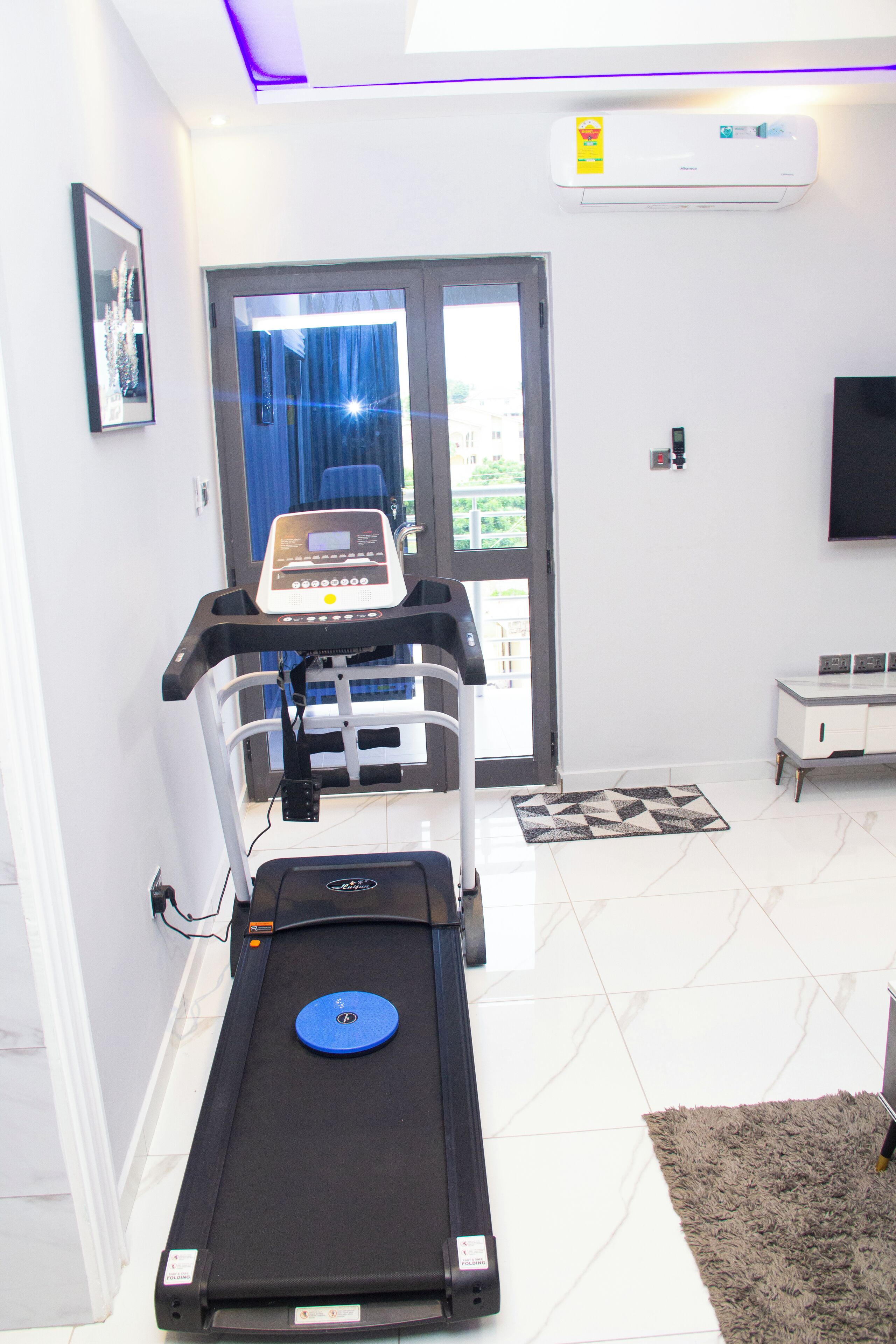 Een sportschool thuis met een loopband, een hometrainer en een bankdrukrek.