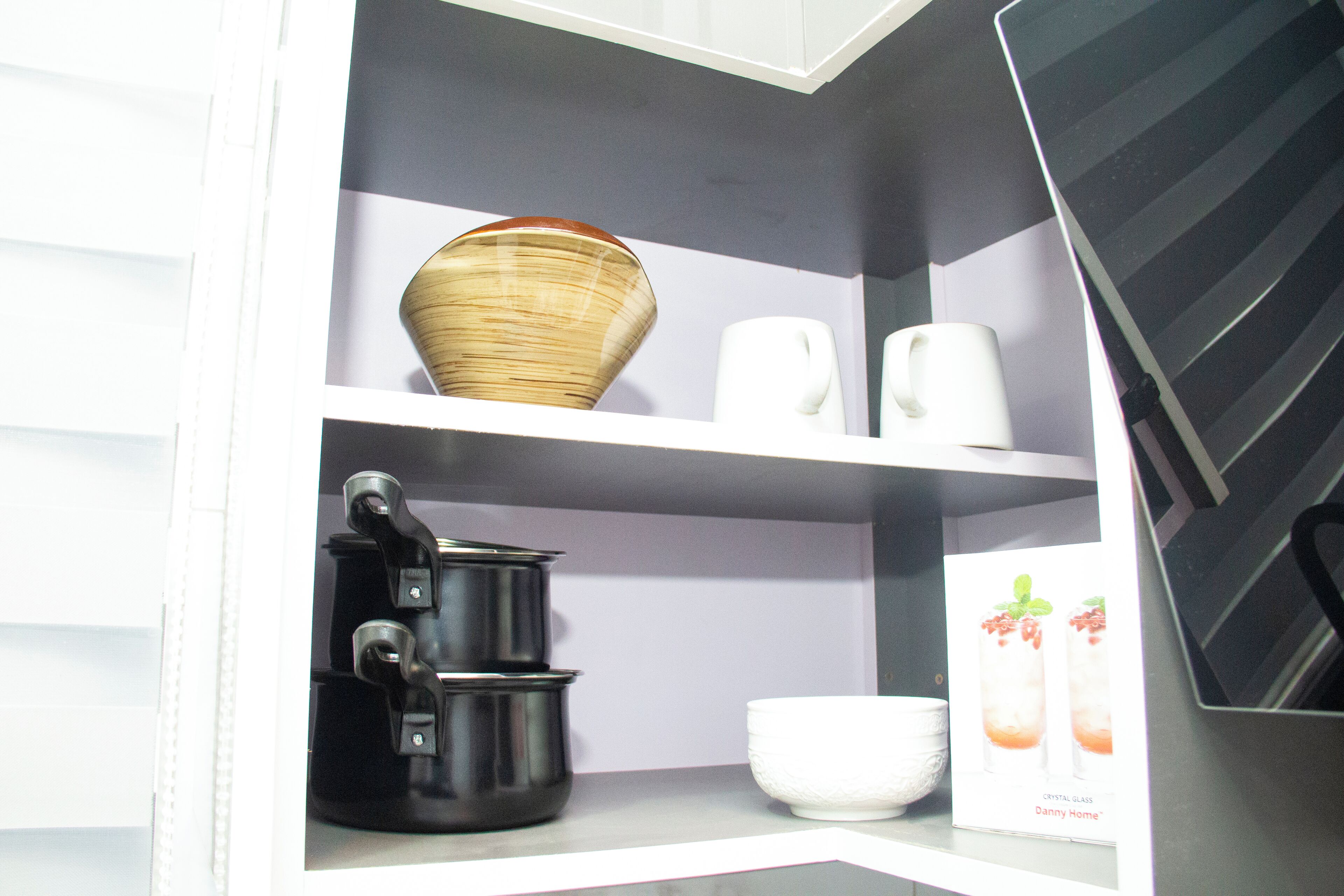 A kitchen with white cabinets, a black pot, a white bowl, and a white mug.