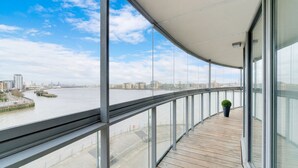A modern building with a curved balcony overlooking a river and cityscape.