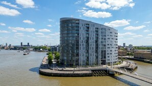 A modern building with a curved facade, located near a river with a bridge and boats.