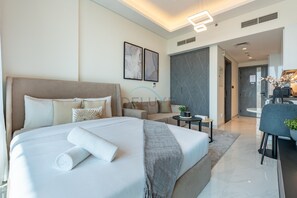 A modern hotel room with a large bed, a sofa, a dining area, and a bathroom visible in the background. - Walking distance to Miracle Garden and Butterfly Garden, Few mins drive to MOE (Dubai)