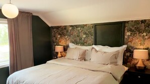 Ein Schlafzimmer mit einem großen Bett, zwei Nachttischen mit Lampen, einem Deckenventilator und blumigem Wandpapier.