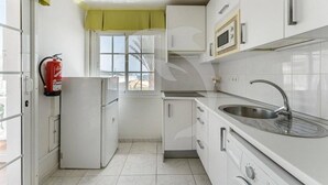 A compact kitchen with white cabinets, a stainless steel sink, and a microwave.